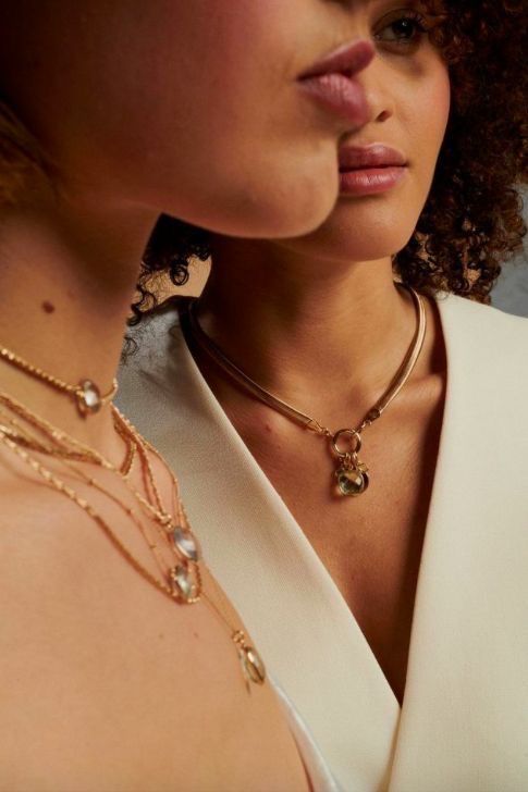 Two models wearing layered gold necklaces